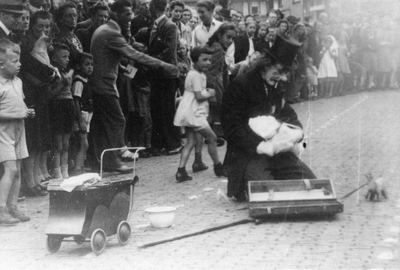 604783 Afbeelding Jo Wilbrink, verkleed als joker, tijdens een act met een baby die Adolf Hitler voorstelt, op het ...